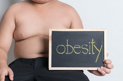 A fat boy holding a blackboard saying obesity