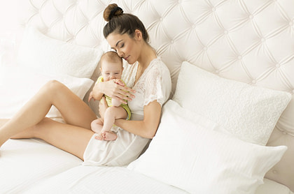 Mother with baby on white bed Post partum recovery