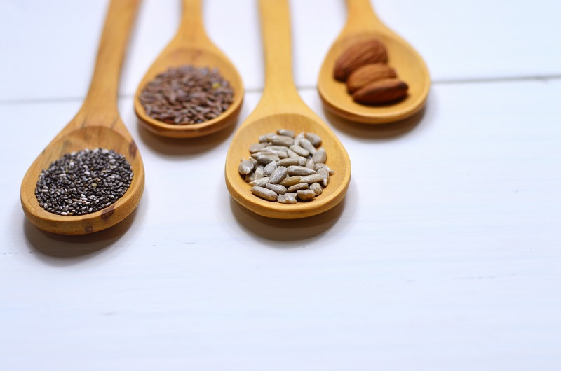Almonds, sunflower seeds, flax seeds and chia seeds on wooden spoons